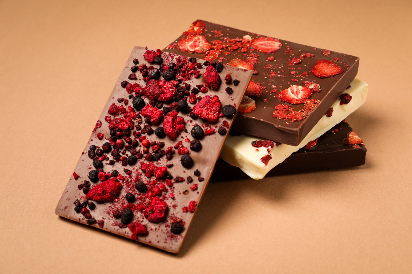Different Chocolate Bars with Freeze Dried Fruits on Beige Backg